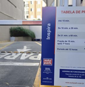 Placa informativa sobre o funcionamento de estacionamento terceirizado no Auto Park, destacando horários e tarifas, para otimizar a terceirização de estacionamentos.