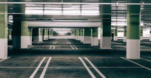 Estacionamento rotativo corporativo vazio em um prédio de estacionamento com múltiplas vagas e pilares de suporte, ideal para empresas que oferecem soluções de mobilidade empresarial.