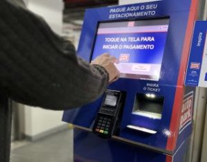 Pessoa usando máquina de pagamento de estacionamento para mostrar que a tecnologia é um dos meios de lucrar com estacionamento.