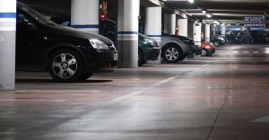 Imagem de estacionamento coberto com pilares vermelhos e carros estacionados, espaço amplo e bem iluminado ideal para estacionamento de veículos.