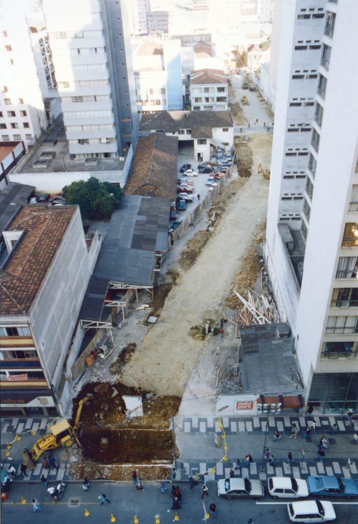 Foto histórica da Autopark obra travessa da lapa: rua em obras com vala aberta entre prédios e máquinas, permitindo a passagem do transporte coletivo.