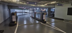 Corredor de estacionamento subterrâneo com vagas demarcadas, barreiras e equipamentos de controle de acesso, representando gestão terceirizada de estacionamento e operação organizada para motoristas.