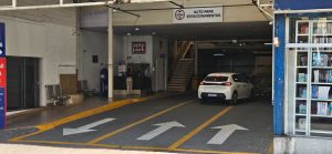 Estacionamento rotativo em shopping com vaga demarcada e entrada do Autopark, com carro no corredor e sinalização de orientação ao fundo.