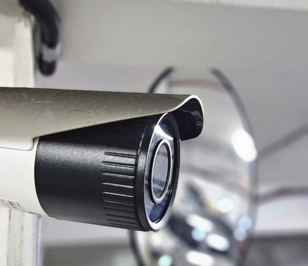 Close-up de uma câmera de segurança instalando em um sistema de monitoramento, com detalhes da lente e do suporte em ambiente interno. Ideal para gestão de estacionamento em shopping.