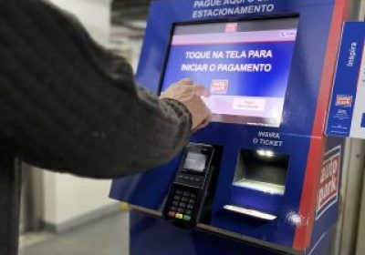Pessoa usando máquina de pagamento de estacionamento para mostrar que a tecnologia é um dos meios de lucrar com estacionamento.