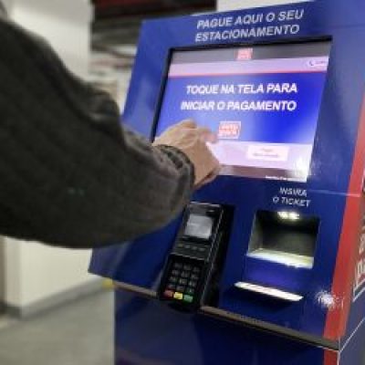 Pessoa usando máquina de pagamento de estacionamento para mostrar que a tecnologia é um dos meios de lucrar com estacionamento.