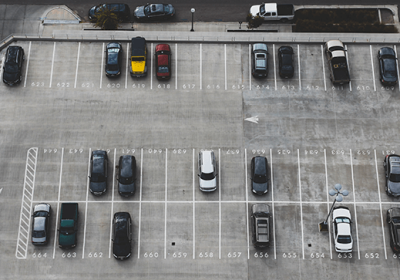 Imagem de um estacionamento ao ar livre com várias vagas disponíveis e alguns veículos, ideal para quem busca onde abrir estacionamento e deseja conhecer opções de locais com vagas.