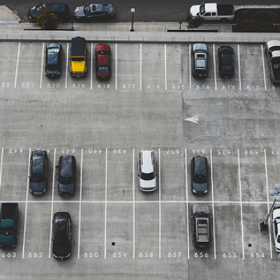 Imagem de um estacionamento ao ar livre com várias vagas disponíveis e alguns veículos, ideal para quem busca onde abrir estacionamento e deseja conhecer opções de locais com vagas.